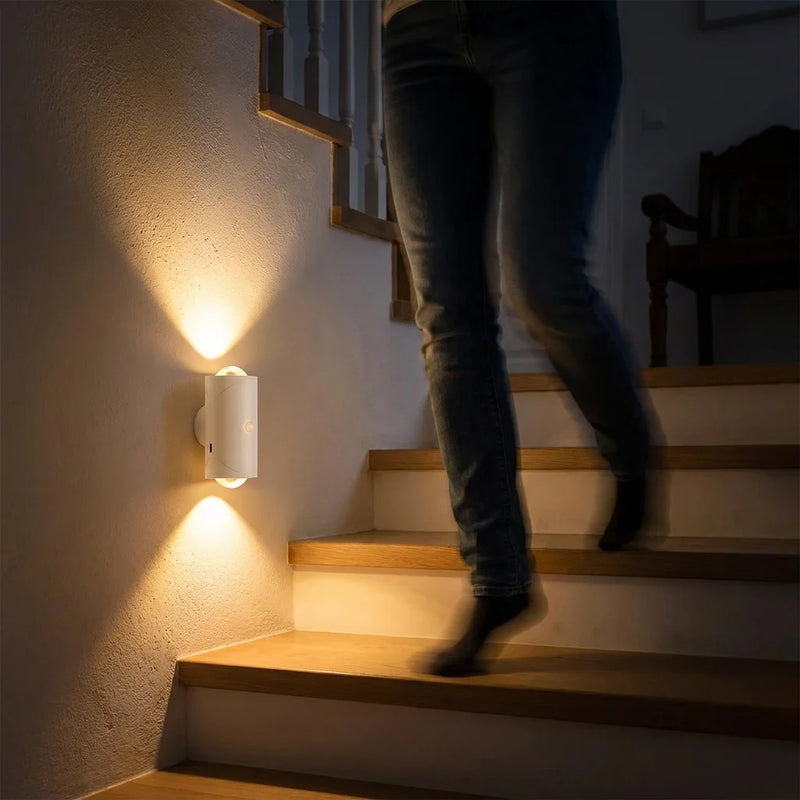 Personne descendant un escalier en bois la nuit, éclairé par une applique murale à détecteur de mouvement sécurisant les marches.