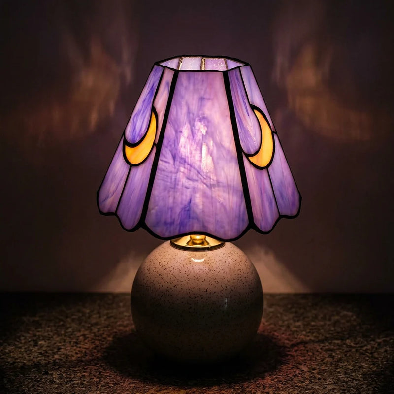 Lampe de chevet céramique vitrail violet lune allumée de nuit, lumière violette tamisée à travers abat-jour verre soufflé, reflets colorés sur mur — Tendre Veilleuse