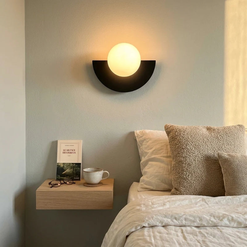 Lampe de chevet design nordique boule G9 allumée au-dessus d'une table de nuit bois clair, draps lin blanc cassé, ambiance chambre scandinave contemporaine, Tendre Veilleuse