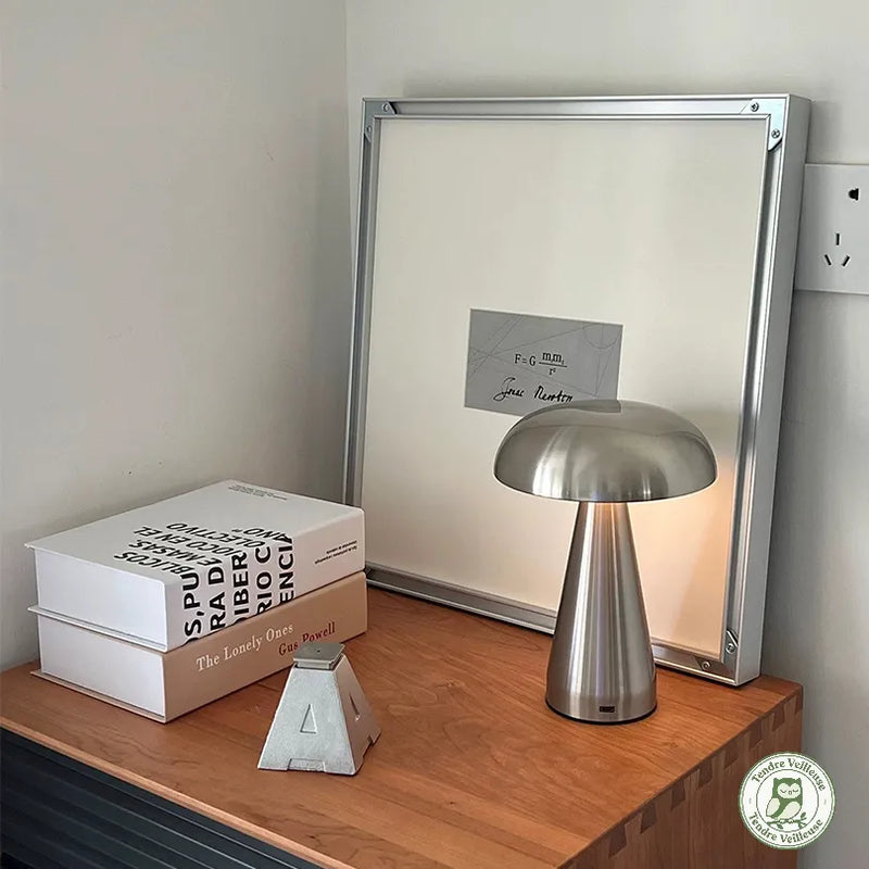 Lampe de chevet tactile sans fil champignon métal brossé
argent sur commode en bois avec livres décoratifs,
lumière LED allumée — Tendre Veilleuse