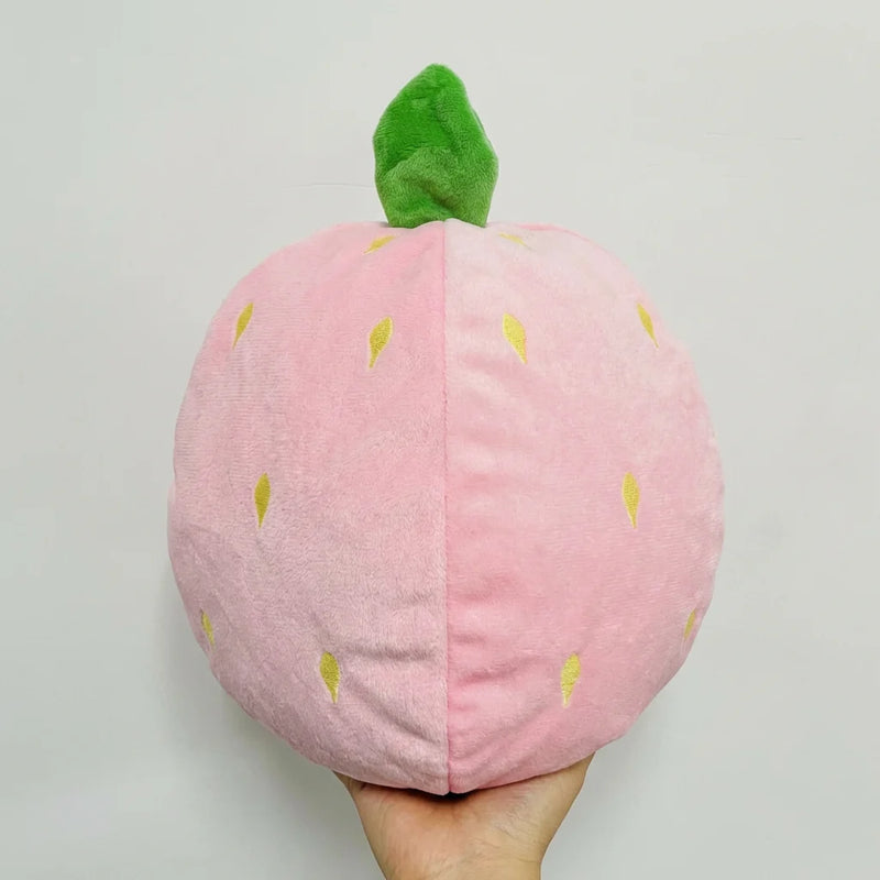 Peluche âne-fraise en position fermée, transformée en une boule compacte en forme de fraise, facile à transporter comme galet anti-stress.