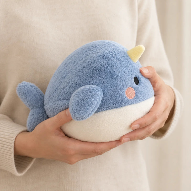 La peluche veilleuse baleine tenue à deux mains par un adulte, montrant sa taille réelle et sa légèreté de 200 grammes