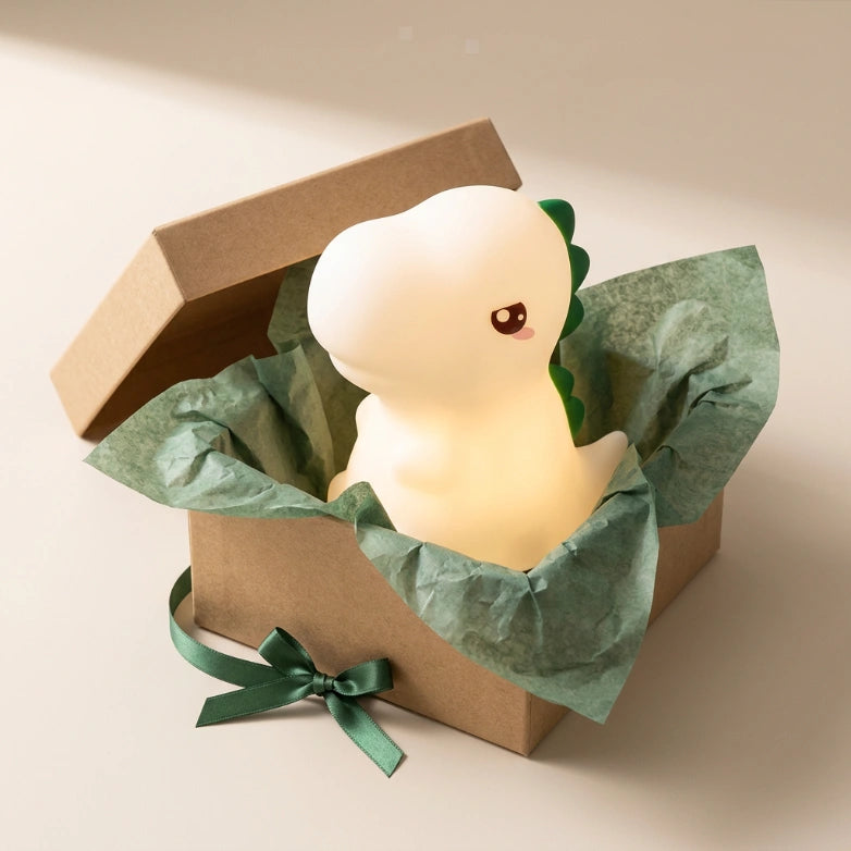 Veilleuse dinosaure posée avec un emballage cadeau, idéale pour offrir à Noël ou un anniversaire d'enfant, Tendre Veilleuse