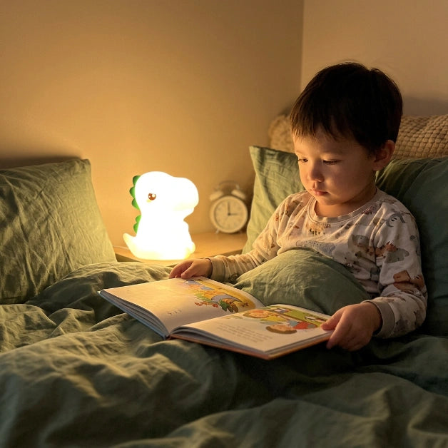 Enfant de 4 ans dans son lit lisant avec la veilleuse dinosaure allumée, lumière douce et sécurisée, Tendre Veilleuse