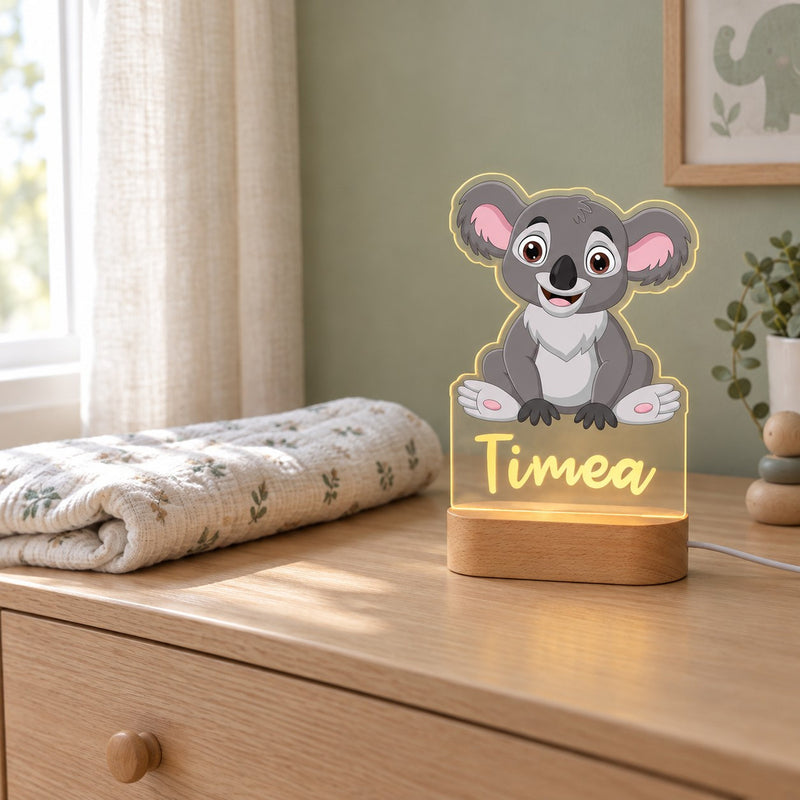 Veilleuse koala personnalisée avec prénom sur une commode en chêne dans une chambre de bébé, le jour