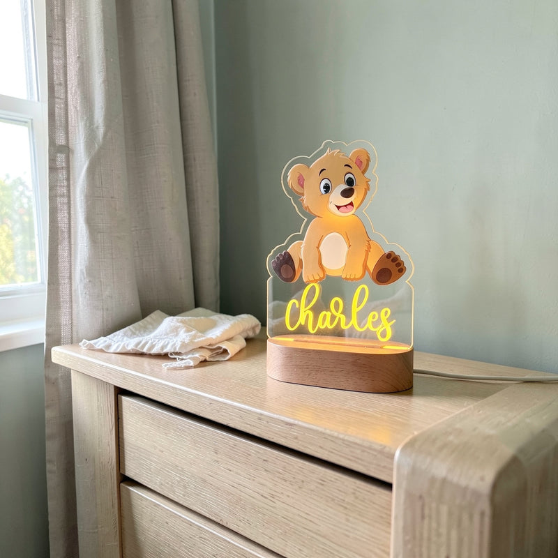 Veilleuse ourson personnalisée avec prénom sur une commode en chêne dans une chambre de bébé, le jour