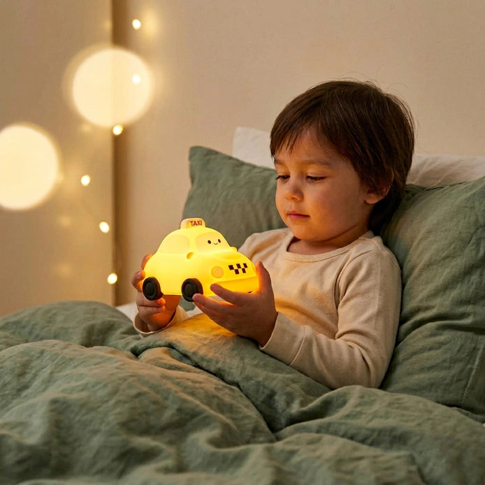 Enfant de 4 ans dans son lit tenant la veilleuse voiture silicone allumée, chambre cosy avec lumière ambiante chaude et douce, qualité photo iPhone — Tendre Veilleuse