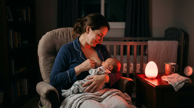 Maman allaitant son bébé la nuit éclairée par une veilleuse rouge en forme d'oeuf sur la table de chevet — Tendre Veilleuse