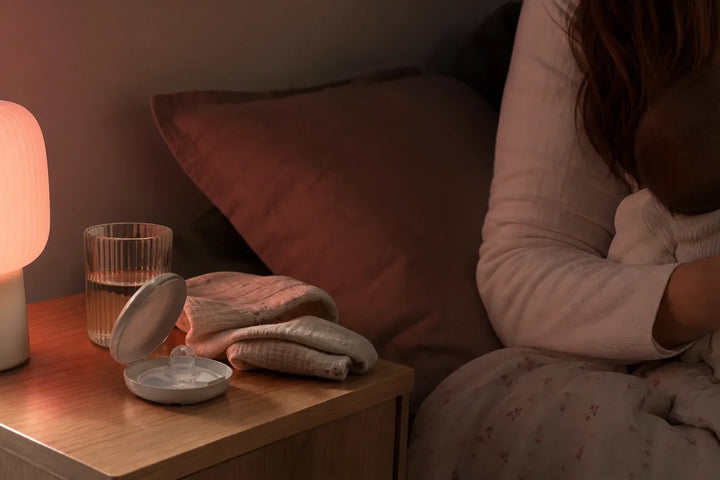 Bout de sein allaitement dans une boite propre sur table de nuit avec lumiere rouge douce pendant une tetee nocturne