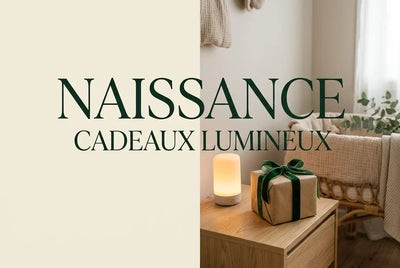 Couverture guide cadeau de naissance 2026 — boîte kraft avec nœud velours vert posée sur table de chevet bois, veilleuse lumière ambrée 2200 K, chambre bébé rattan en fond flou