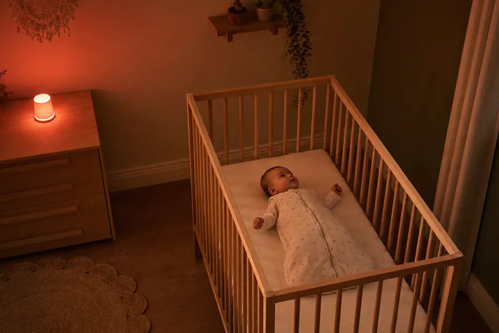 Crise des 8 mois : bébé éveillé sur le dos dans un lit dégagé, veilleuse rouge hors du lit, Tendre Veilleuse.