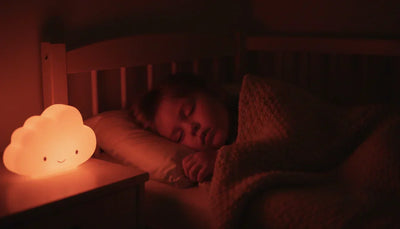 Enfant endormi dans son lit avec une veilleuse à lumière rouge de faible intensité allumée pendant la nuit, Tendre Veilleuse