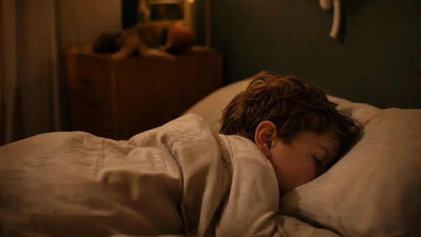Enfant de 5 ans endormi dans une chambre éclairée en ambre, illustration du grincement de dents nocturne, Tendre Veilleuse