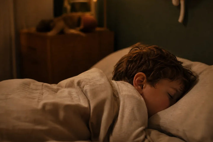 Enfant de 5 ans endormi dans une chambre éclairée en ambre, illustration du grincement de dents nocturne, Tendre Veilleuse