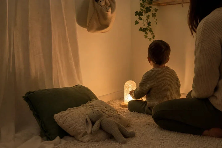 Espace Snoezelen à la maison avec lumière chaude, enfant autonome et adulte présent, Tendre Veilleuse