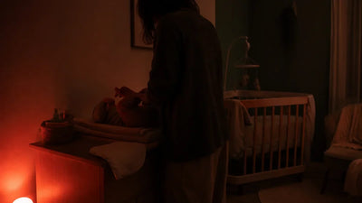 Chambre de bébé éclairée par une lumière rouge de très faible intensité pendant un change nocturne, Tendre Veilleuse