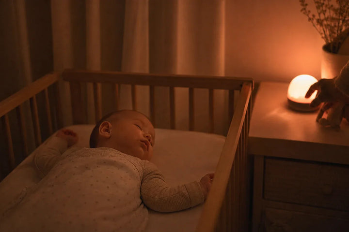 Mélatonine bébé sommeil naturel avec nourrisson endormi sous veilleuse lumière chaude qui préserve l'hormone du sommeil
