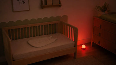 Veilleuse bébé à quel âge : chambre de nourrisson sombre avec veilleuse rouge douce posée hors du lit