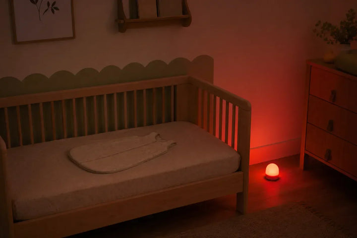 Veilleuse bébé à quel âge : chambre de nourrisson sombre avec veilleuse rouge douce posée hors du lit