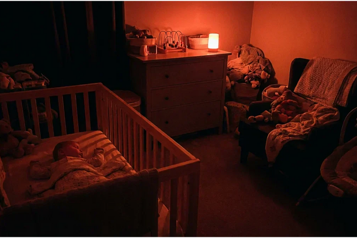 Chambre de bébé apaisée par une veilleuse lumière rouge. L'utilisation d'un spectre lumineux supérieur à 620 nanomètres protège les cellules ipRGC et garantit la sécrétion continue de mélatonine pour un sommeil profond et sans danger.