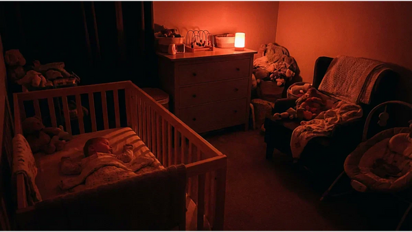 Chambre de bébé apaisée par une veilleuse lumière rouge. L'utilisation d'un spectre lumineux supérieur à 620 nanomètres protège les cellules ipRGC et garantit la sécrétion continue de mélatonine pour un sommeil profond et sans danger.
