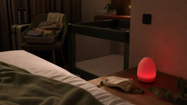 Veilleuse portable bébé voyage dans une chambre d'hôtel avec lit parapluie et lumière rouge douce