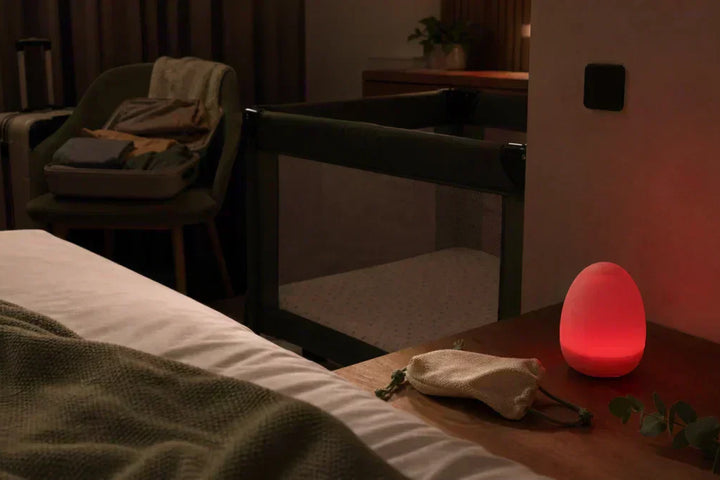 Veilleuse portable bébé voyage dans une chambre d'hôtel avec lit parapluie et lumière rouge douce