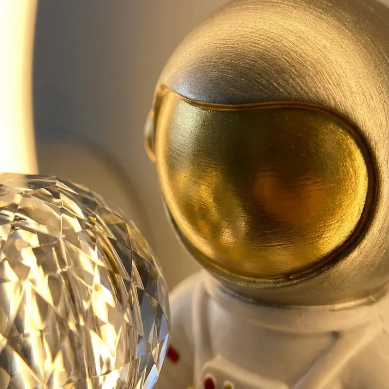 Gros plan sur le casque doré et la sphère cristal de la veilleuse murale astronaute projection.