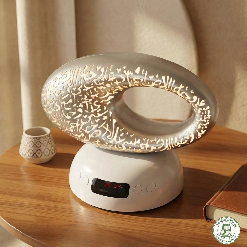 Diffuseur coranique et humidificateur design argenté sculpté avec calligraphie arabe lumineuse affichant l'heure sur une table en bois.
