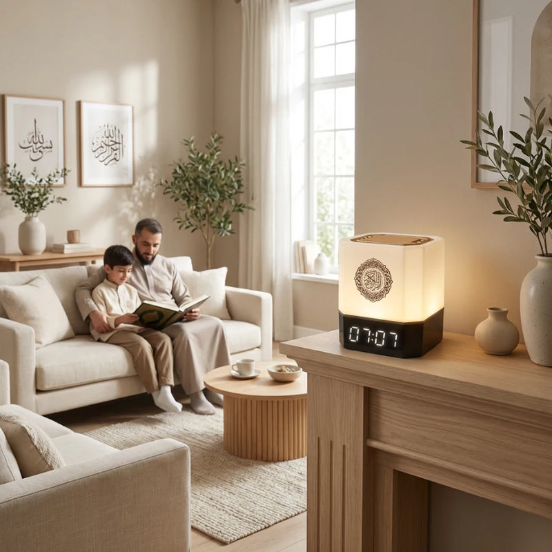 Père et fils lisant le Coran sur le canapé du salon avec l'horloge Azan cube affichant l'heure au premier plan.