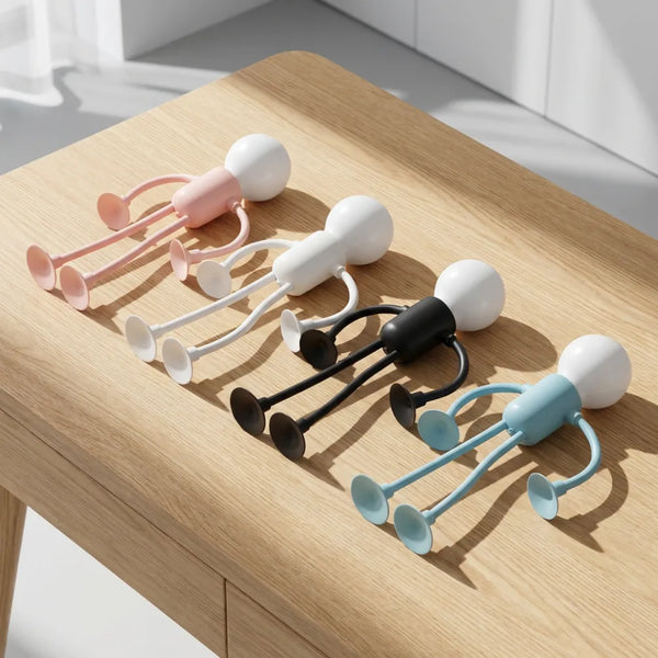 Quatre lampes de chevet originales en forme de petit robot articulé et flexible, disponibles en rose, blanc, noir et bleu, posées sur une table en bois. Cette lampe ludique sans fil est un cadeau idéal pour enfant et ado, parfaite pour le bureau ou comme compagnon de lecture.