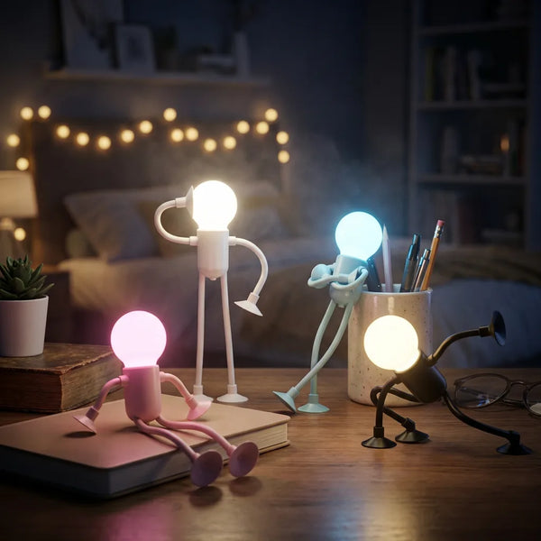 Scène de chambre cosy avec quatre lampes de chevet robot articulées et allumées. La lampe rose diffuse une lumière douce sur un livre, la blanche éclaire le bureau, la bleue sert de compagnon de lecture près des stylos, et la noire est dans une pose ludique. Ces lampes flexibles créent une ambiance chaleureuse pour les enfants et les ados.
