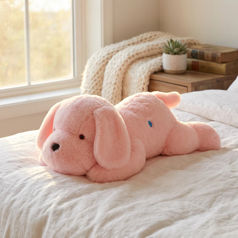 Peluche lumineuse chien rose allongée sur un lit blanc, servant de grand coussin veilleuse doux et décoratif en journée.