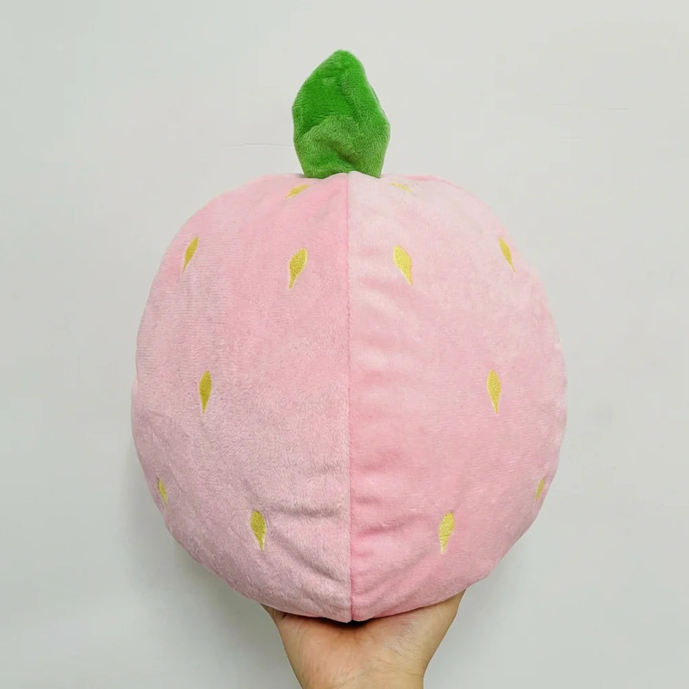 Peluche âne-fraise en position fermée, transformée en une boule compacte en forme de fraise, facile à transporter comme galet anti-stress.