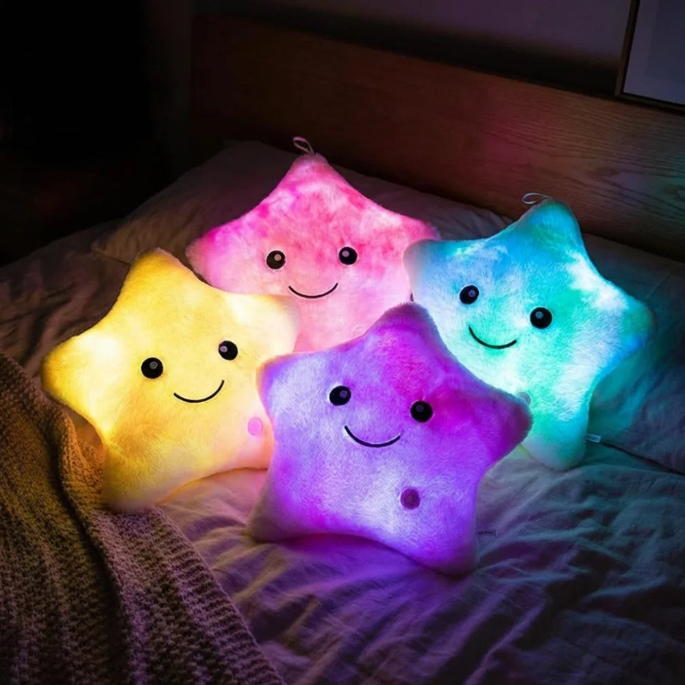 Collection de quatre peluches lumineuses étoiles aux couleurs variées (jaune, rose, violet, bleu) posées sur un lit, créant une ambiance déco kawaii et féerique.