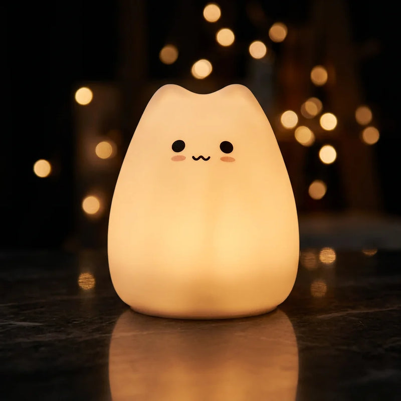 Veilleuse chat tactile Tofu™ allumée en lumière ambre chaude sur fond sombre, silicone souple 0,3W — Tendre Veilleuse
