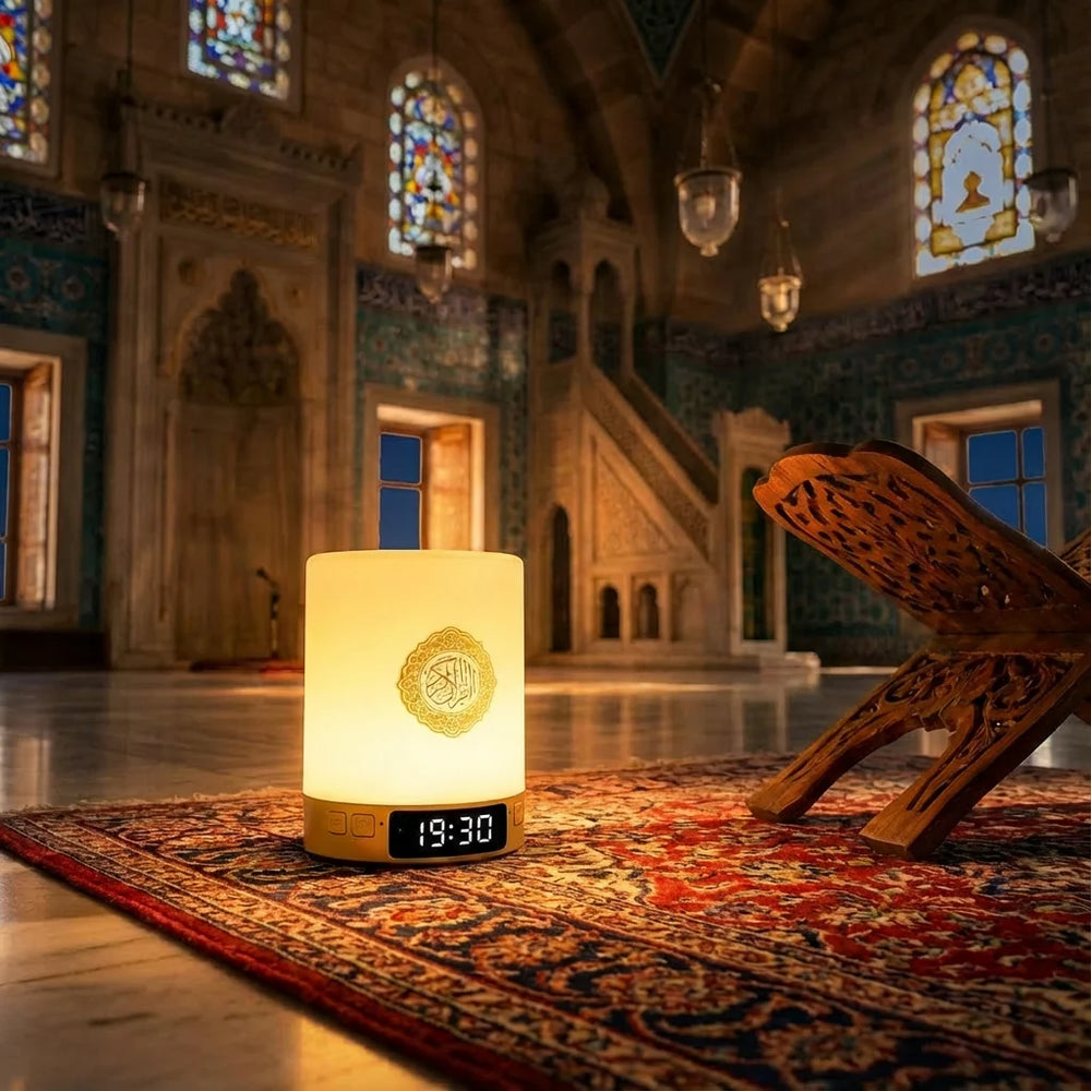 Veilleuse coranique en fonction, diffusant une lumière chaude dorée. L'écran LED affiche l'heure 19:30. Posée dans une mosquée près d'un porte-Coran.
