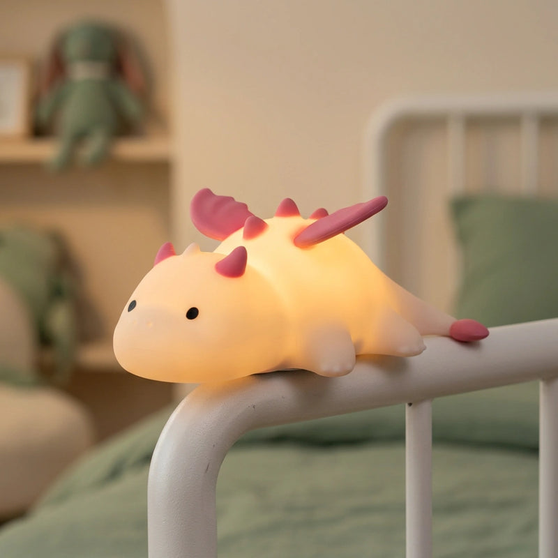 Veilleuse dinosaure silicone allumée et fixée magnétiquement sur le montant en métal blanc d'un lit d'enfant, montrant la fonctionnalité aimantée — Tendre Veilleuse