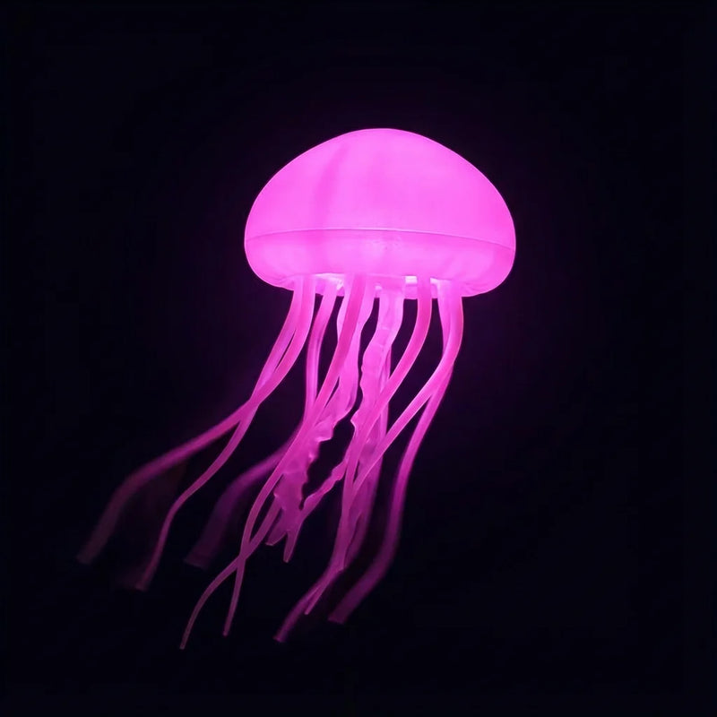 Veilleuse en forme de méduse rose luminescente flottant dans l'obscurité totale, ses tentacules créant un effet visuel hypnotique pour apaiser l'anxiété nocturne et la peur du noir.