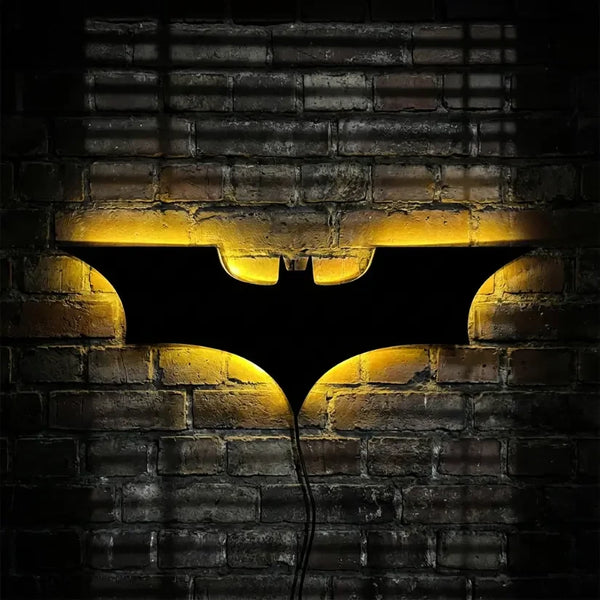 Veilleuse murale Batman rétroéclairée jaune sur mur de briques sombres style Gotham industriel.