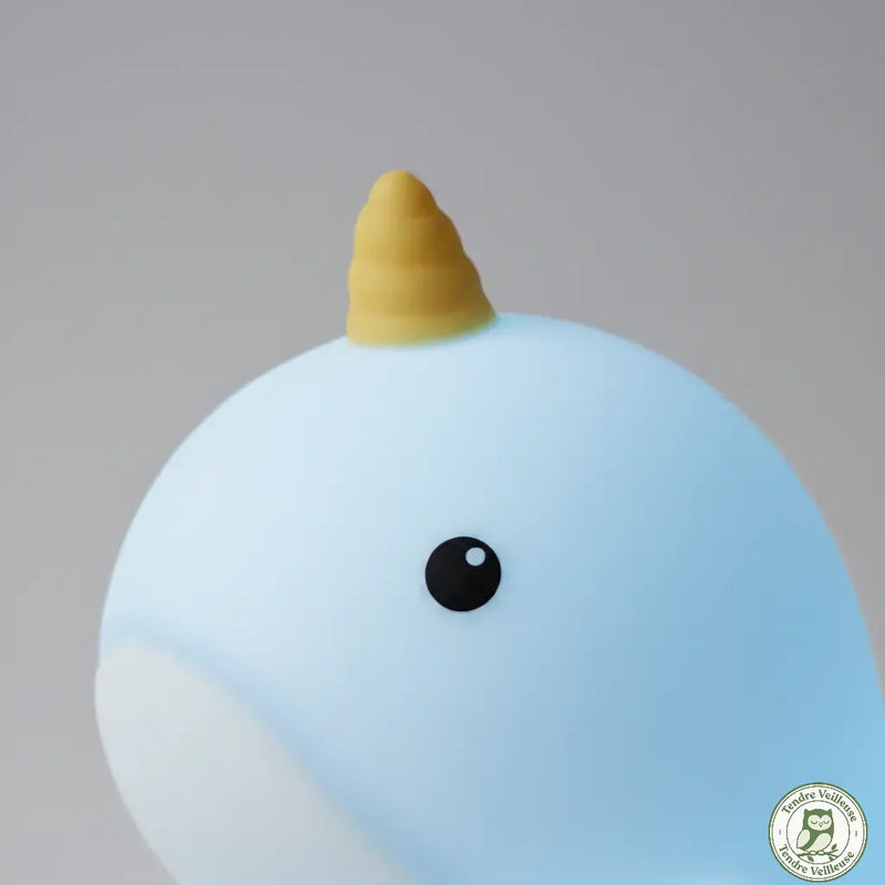 Gros plan sur la tête de la veilleuse narval bleue montrant la texture en silicone souple et la corne dorée