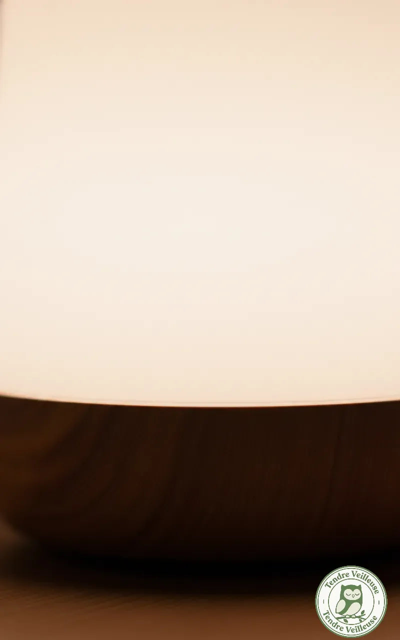 Gros plan sur le socle en bois naturel et la diffusion d'une lumière blanche chaude par la veilleuse.