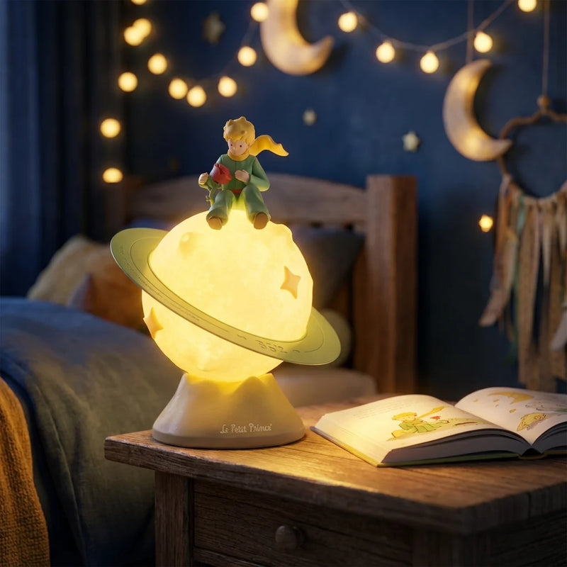 La Veilleuse Petit Prince allumée diffuse une lumière chaude apaisante sur une table de chevet la nuit, accompagnée de guirlandes lumineuses pour le rituel du coucher.