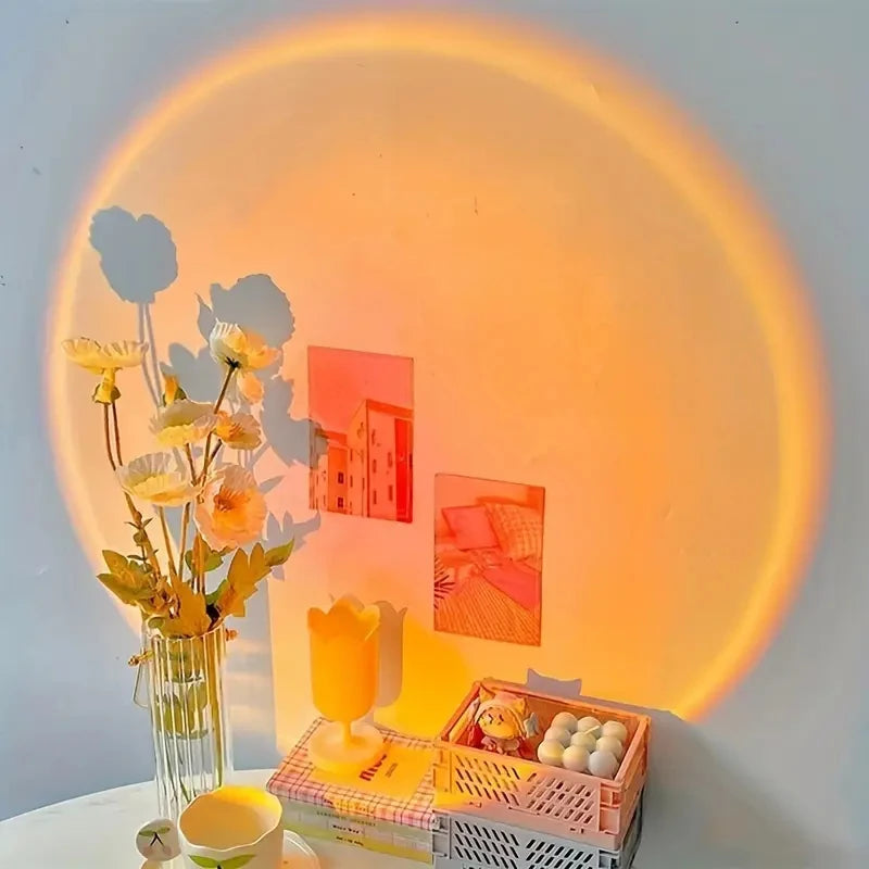 Projection lumineuse coucher de soleil créant un fond esthétique sur un mur blanc, mettant en valeur des ombres portées de fleurs et une décoration de bureau tendance.