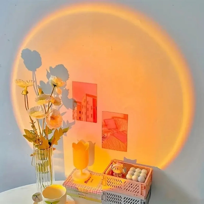 Veilleuse projection coucher de soleil, halo orange chaud projeté sur un mur clair au-dessus d’un bureau décoré fleurs et objets déco cosy — Tendre Veilleuse