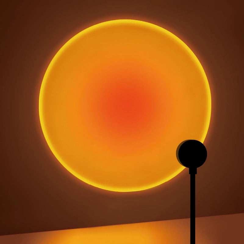 Projection lumineuse circulaire orange et jaune imitant un coucher de soleil sur un mur sombre, créée par la veilleuse projecteur LED rotative.