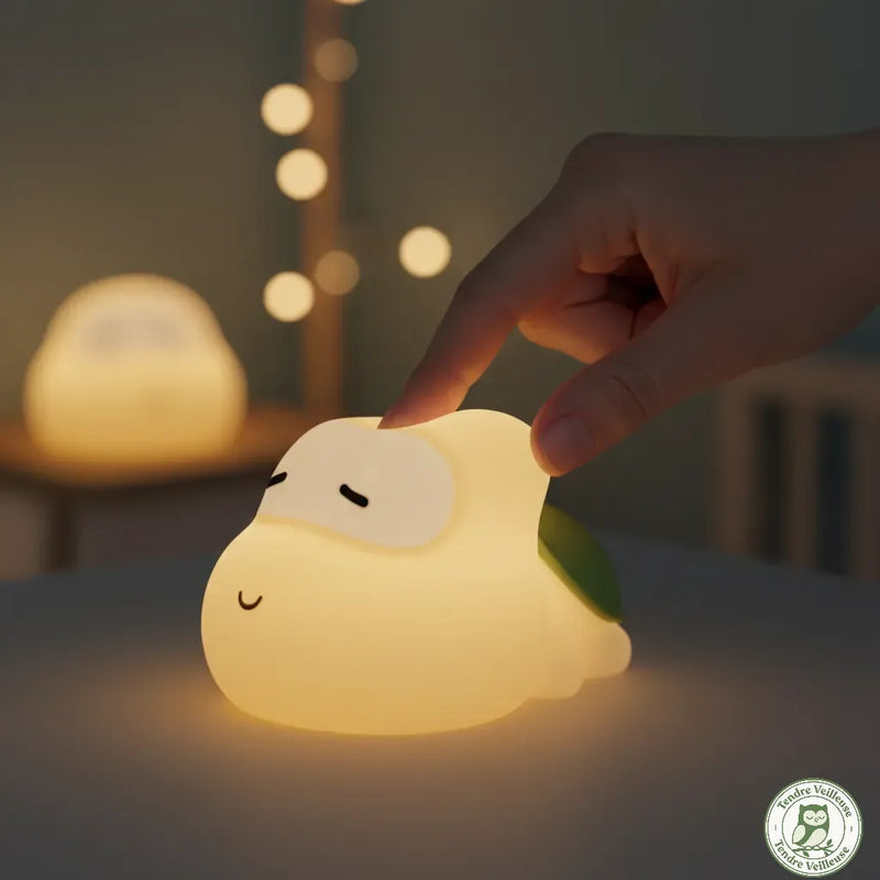 Doigt appuyant sur la carapace silicone de la veilleuse tortue Titou pour activer la commande tactile, lumière chaude allumée — Tendre Veilleuse